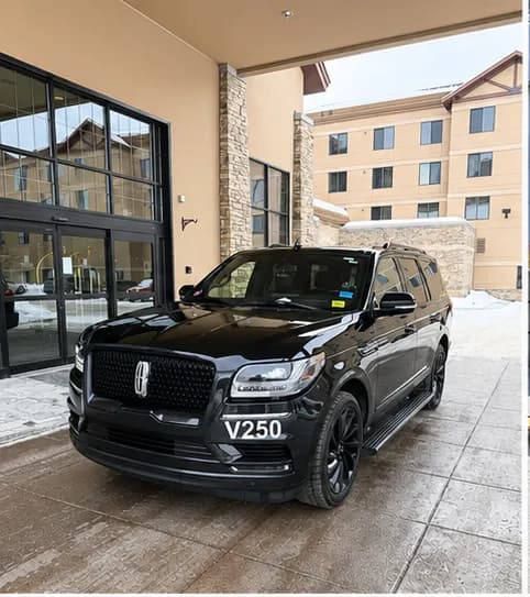 Black Lincoln Navigator at a mountain-lodge entrance after fresh snow, Alaska